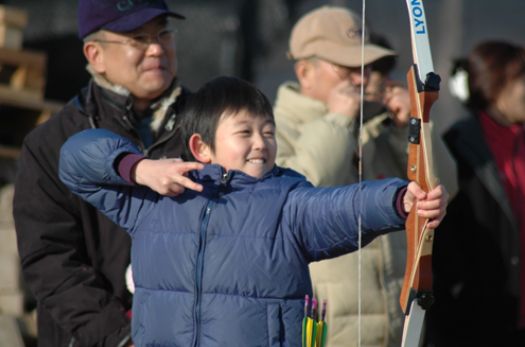 A child drawing a bow at the archery range